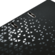 Schwarze Oberfläche mit geometrischem Muster aus kleinen, glänzenden Dreiecken und zwei Löchern für eine Bindung.