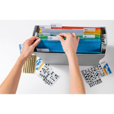 Hände sortieren farbige Akten in einem Ordner mit beschrifteten Trennblättern. Daneben liegen Aufkleber mit Buchstaben.